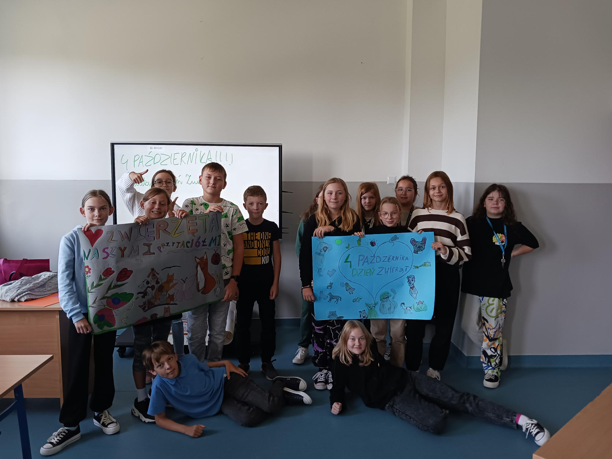Zdjęcie grupowe przedstawiające uczniów z plakatami z okazji Światowego Dnia Zwierząt.