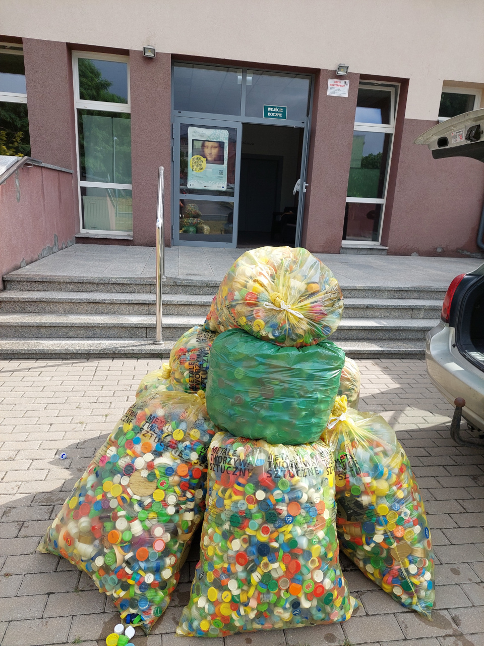 Zdjęcie przedstawiające nakrętki w workach stojące przed Domem Kultury w Opatowie
