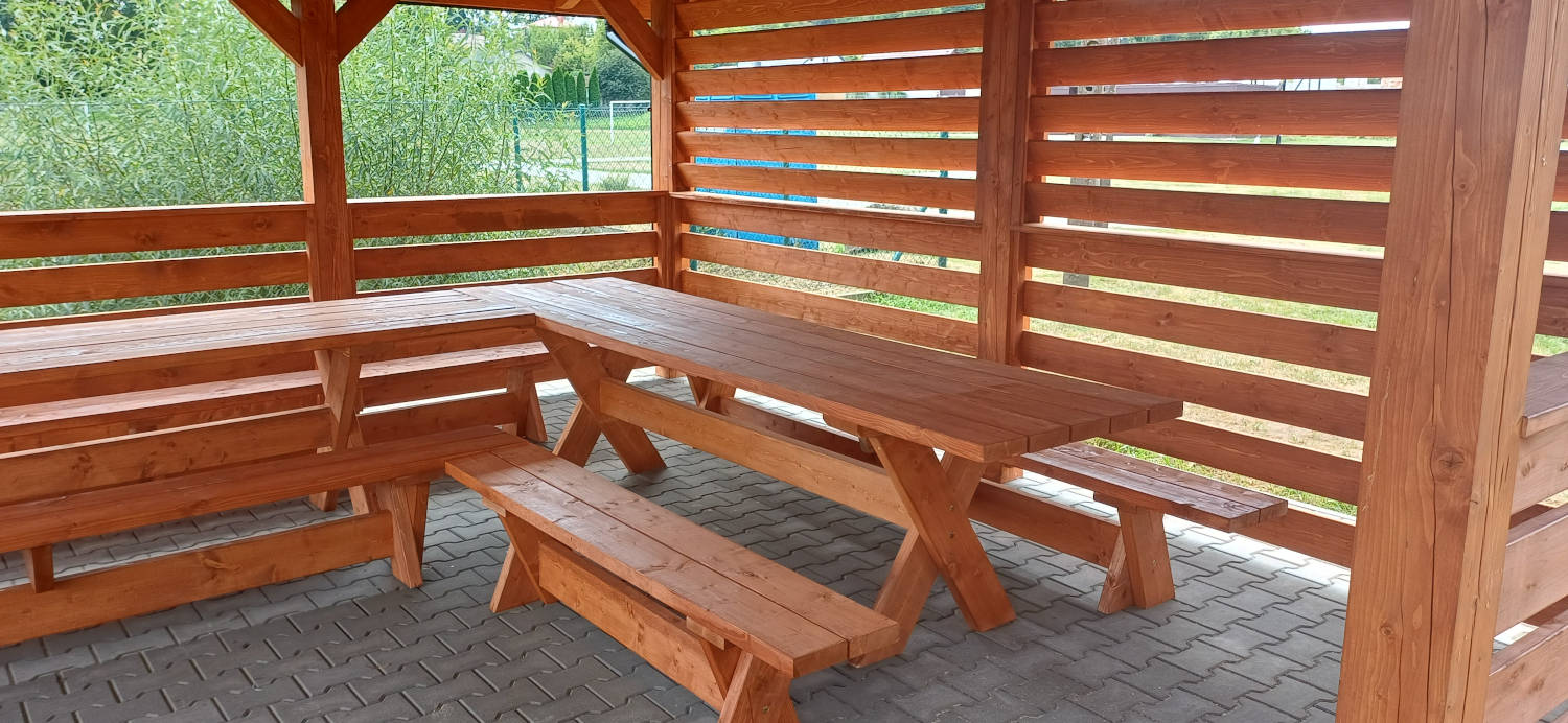 Drewniane ławki i stoły we wnętrzu altany
