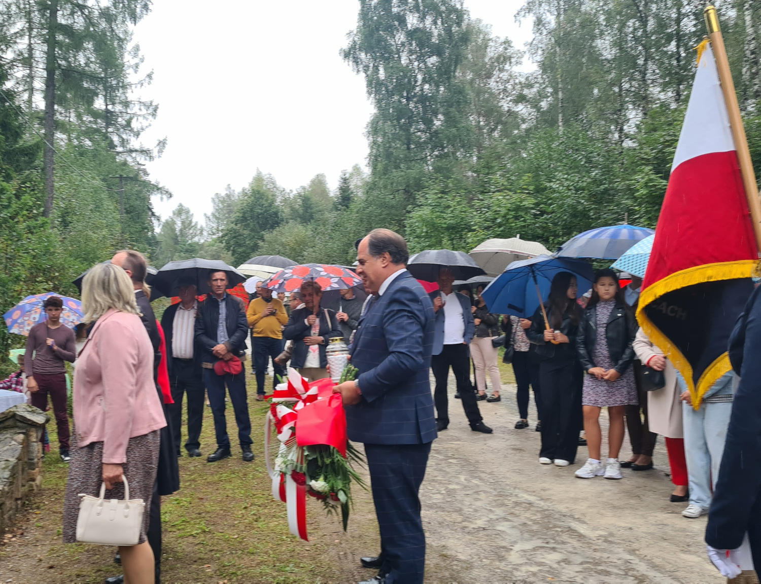 Uczczono pamięć o mieszkańcach dawnych Orłowin Wójt Gminy Wojciechowice z wiązanką w ręce, w tle zgromadzeni ludzie na uroczystości